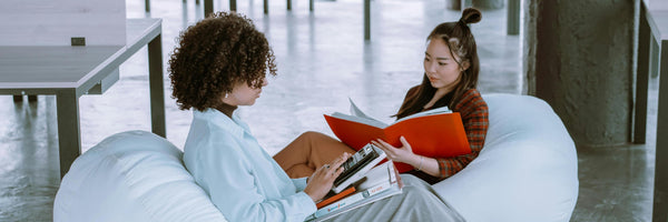 two women reading books on bean bags