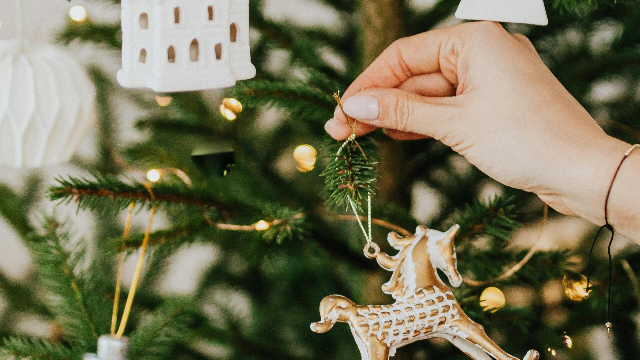 hand hanging christmas decoration onto tree